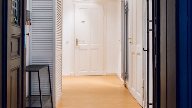 A hallway with a wooden floor, white doors, and a black metal bench. - 3-room guest apartment close to the center, suitable for 1 - 4 persons (Leipzig)