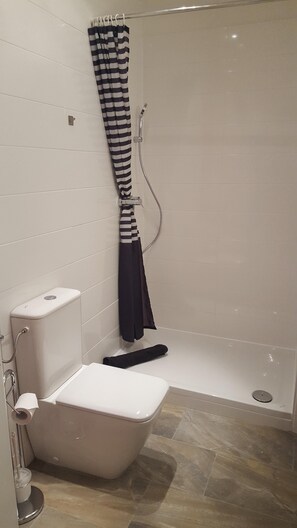 Bathroom features a toilet, bidet, and shower area with a striped shower curtain.