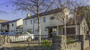 A white building with a sign that reads "Motel Luxury Accommodation." - Kauri Motel (Christchurch)