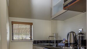 A compact kitchen with a microwave, sink, and stainless steel dishwasher. - Kauri Motel (Christchurch)