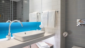 Une salle de bain moderne avec un lavabo blanc, un miroir et des toilettes.