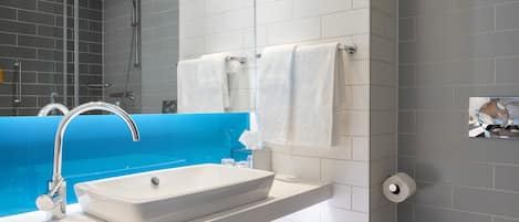 Un baño moderno con un lavamanos blanco, un espejo y un inodoro.