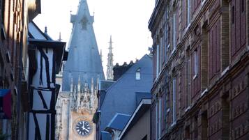 Una calle estrecha con edificios históricos, una imponente torre del reloj y la aguja de una iglesia.