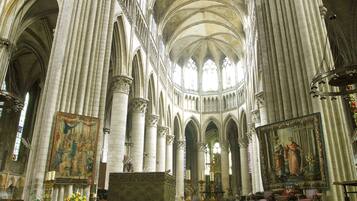 Interior de una catedral con altos techos abovedados, amplias vidrieras y un área de altar central.