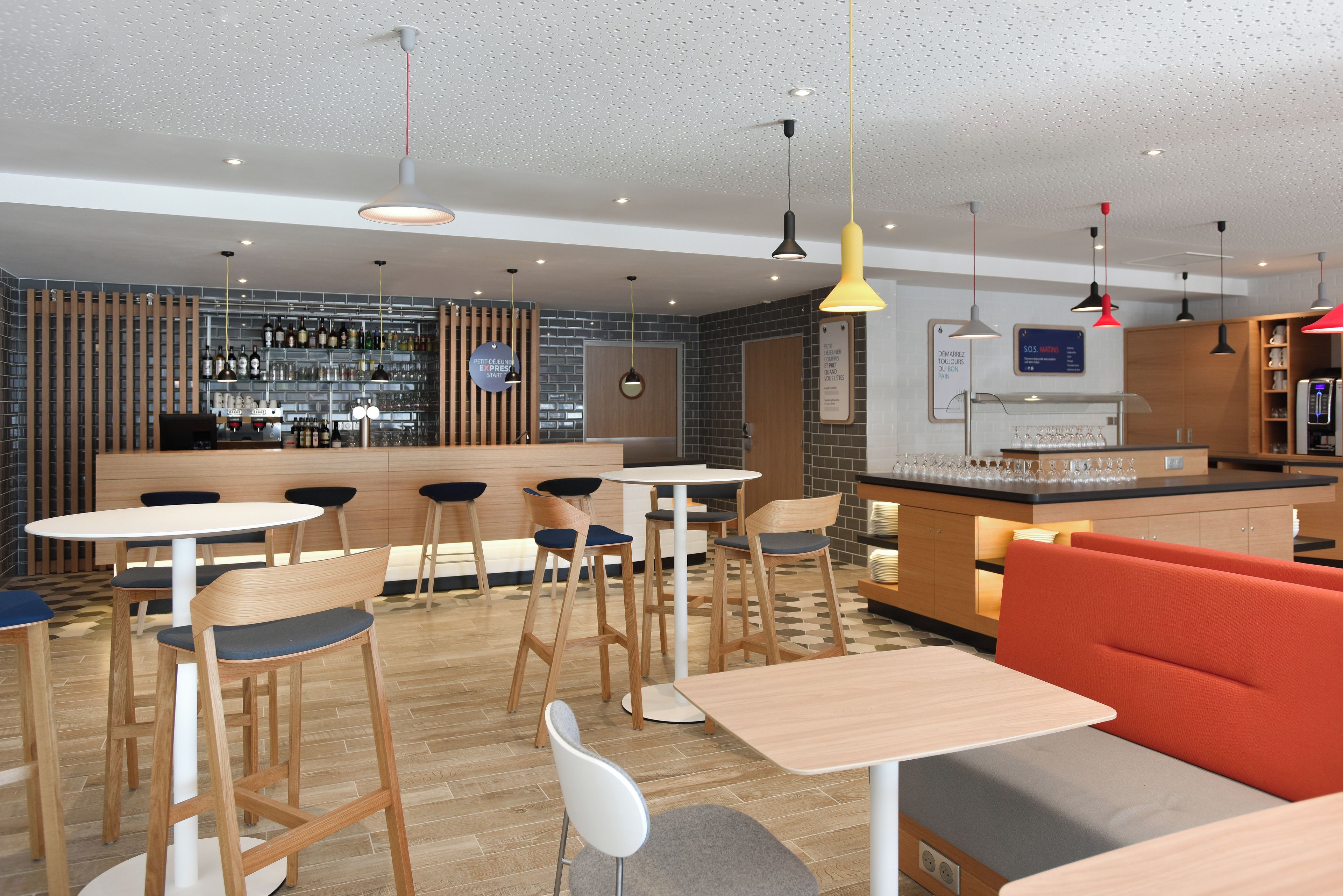 Een moderne bar met een toog, krukken en diverse flessen en glazen.