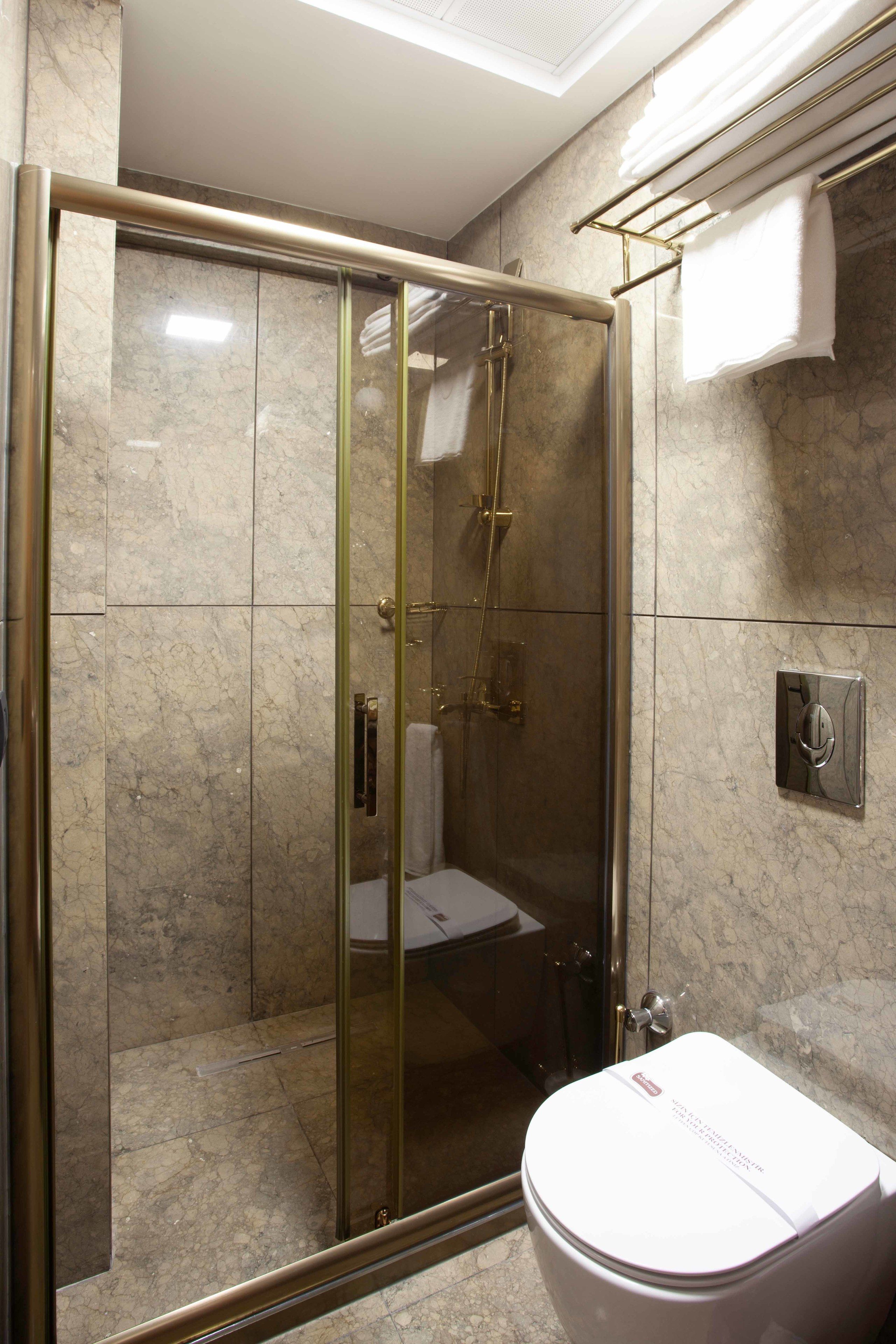 Un baño moderno con ducha de vidrio, inodoro y toallero.