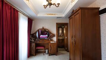 A room with a wooden desk, a mirror, a wardrobe, and a chandelier.