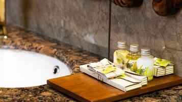 A bathroom sink with toiletries on a wooden tray.