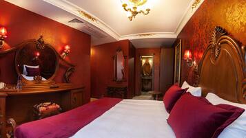 A hotel room with a large bed, a vanity with a mirror, and two wall sconces.