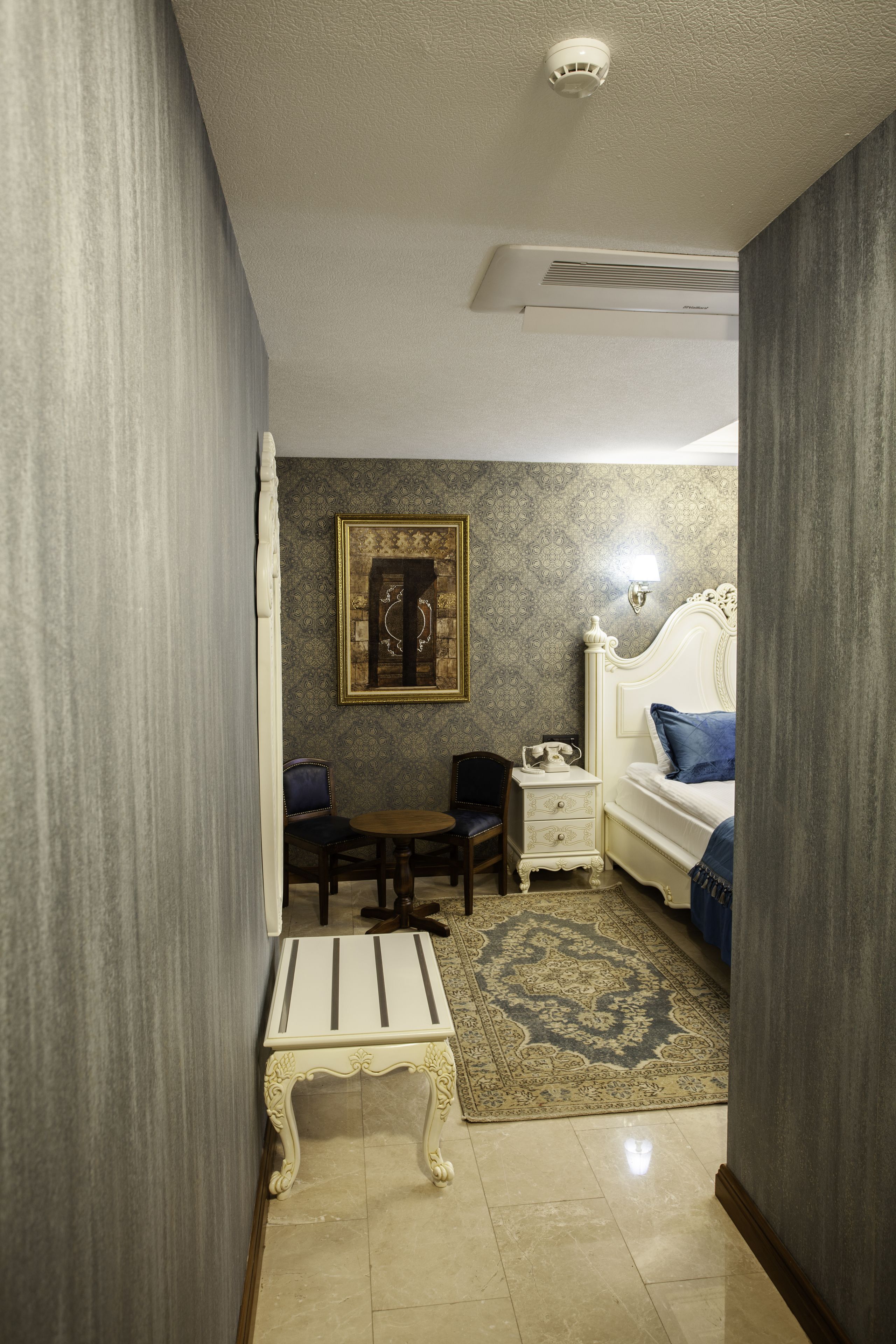 A bedroom with a bed, bedside table, chair, and a rug.