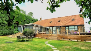 A modern house with a tiled roof, a glass conservatory, and a wooden deck. - My Way Guest House (Durham)