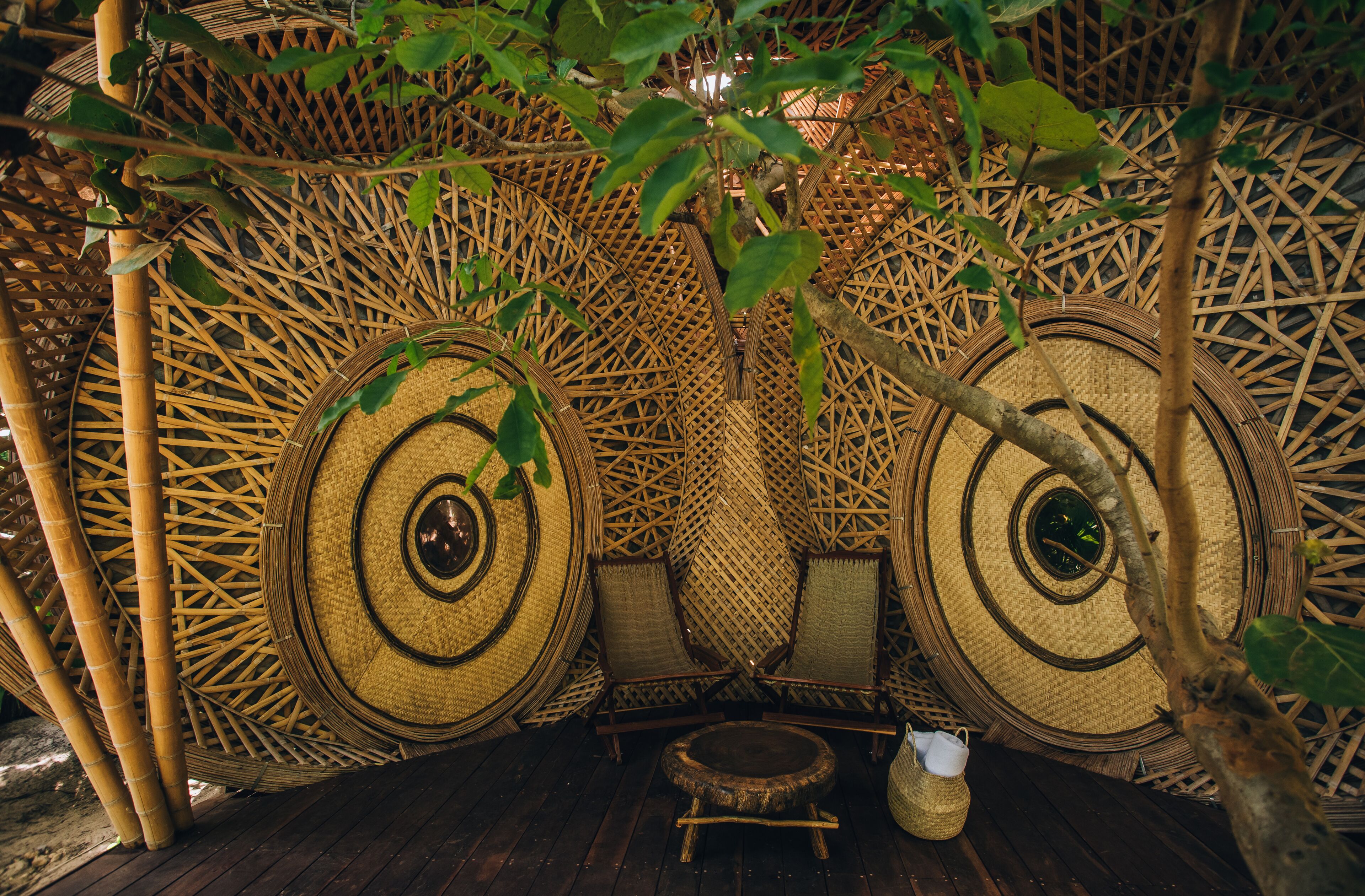 Une structure traditionnelle en bambou, avec des nattes tissées et une petite table en bois.