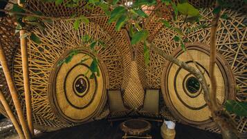 Une structure traditionnelle en bambou, avec des nattes tissées et une petite table en bois.