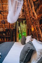 A bed with a canopy in a rustic wooden room with a natural view.
