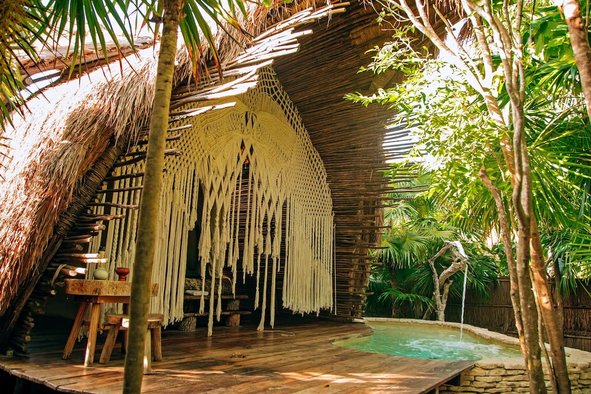 A thatched-roof structure with a pool and wooden furniture.