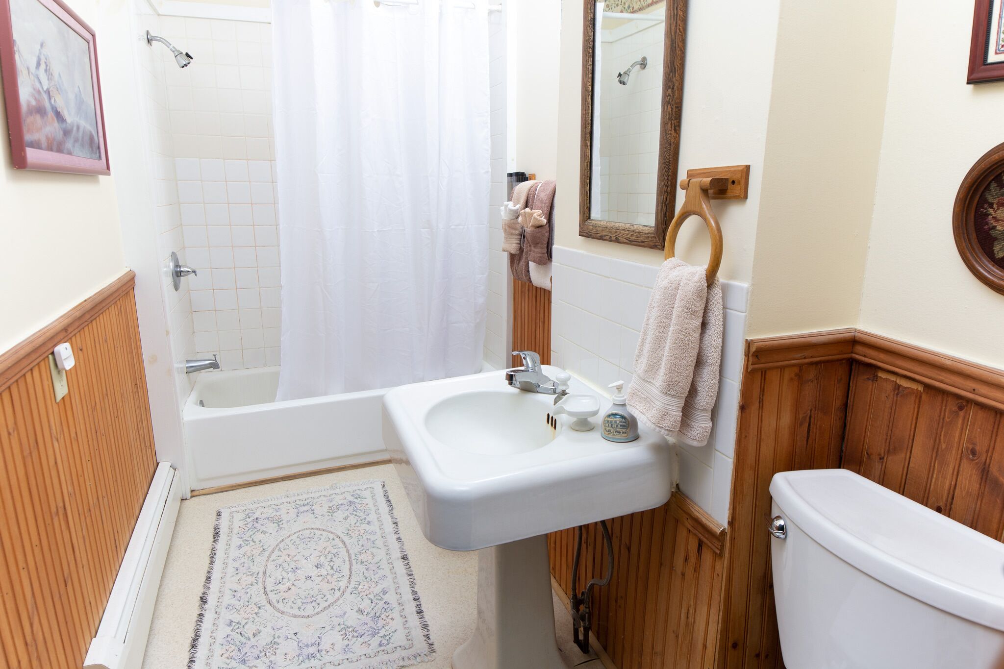 A bathroom with a bathtub, sink, mirror, and toilet.