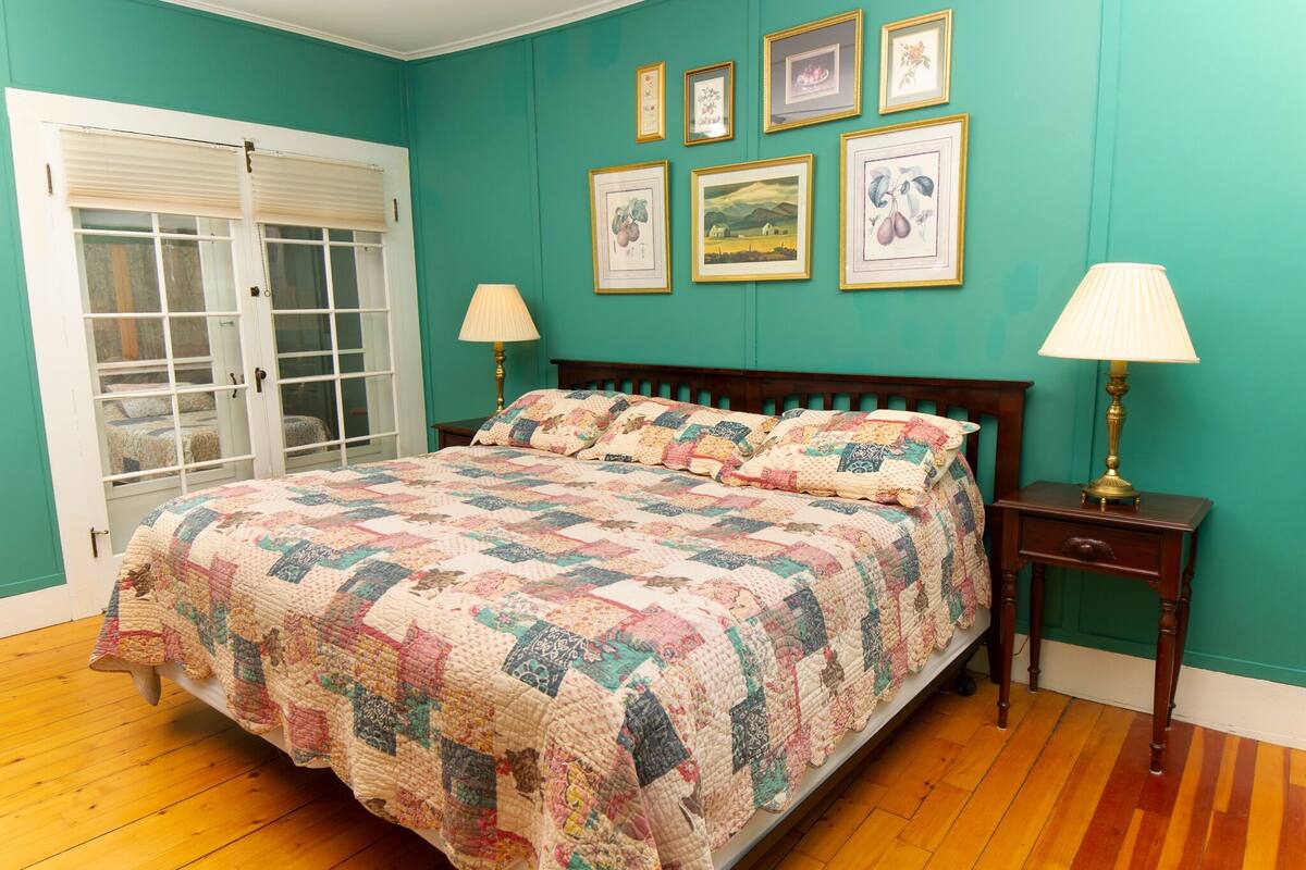 A bedroom with a wooden bed, teal walls, and framed pictures.