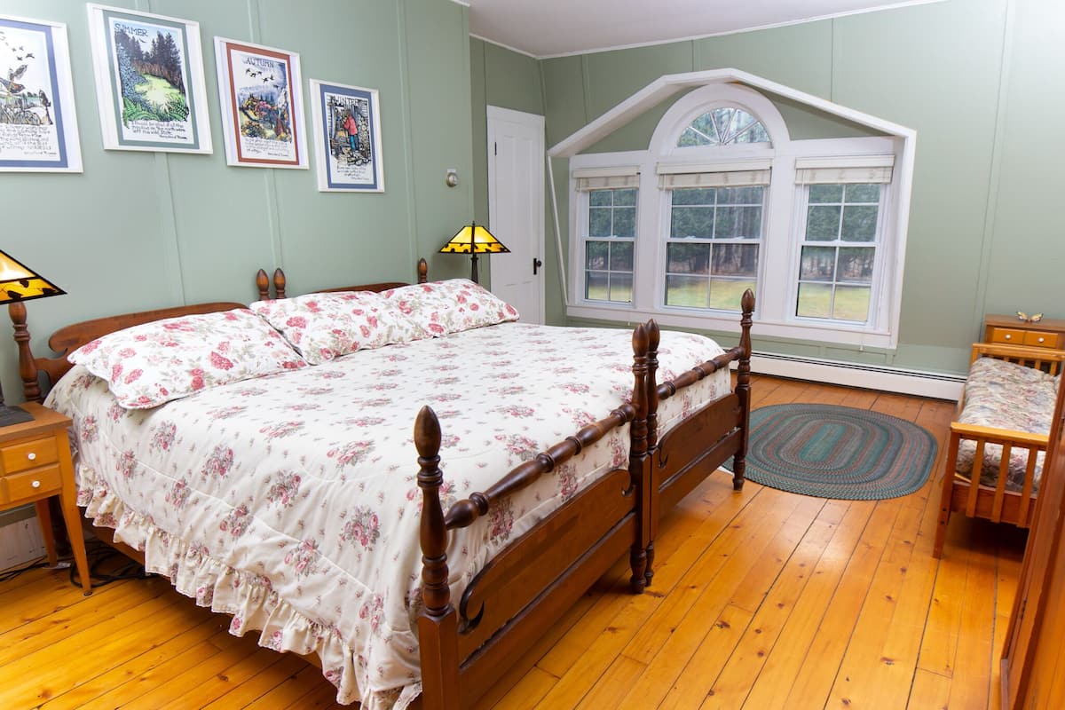 A bedroom with a wooden bed, a window with a view, and a door.