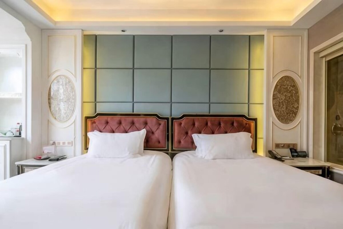 A double bed with a tufted headboard, a bedside table, and a wall-mounted telephone.