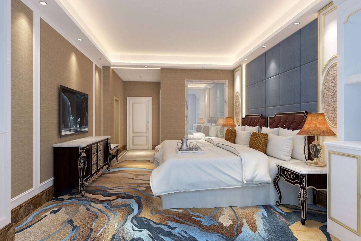 A hotel room with a large bed, a bedside table with a lamp, a dresser, and a mirror.