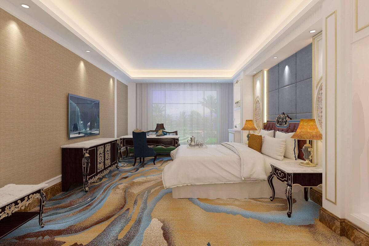 A hotel room with a large bed, a desk, a chair, and a view of palm trees through the window.