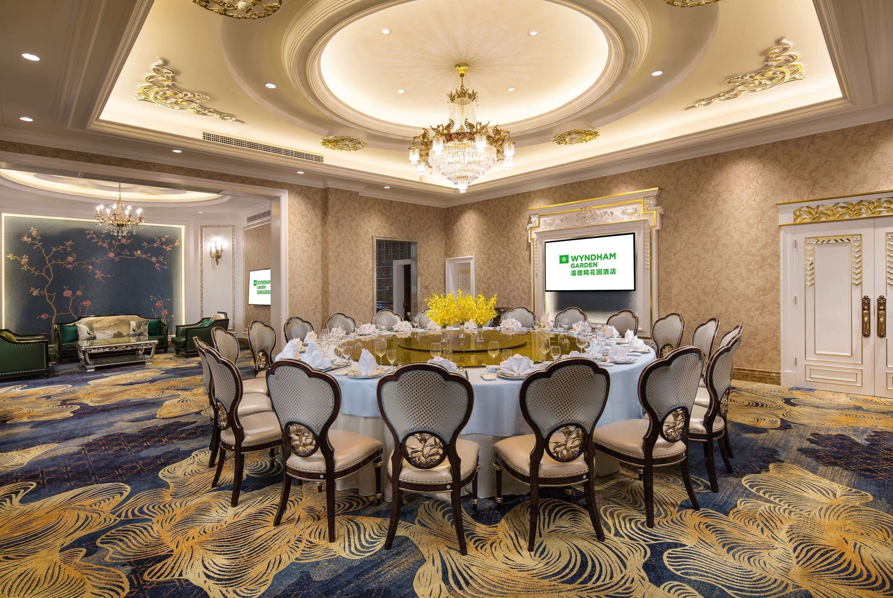 Une salle de banquet avec une table ronde dressée pour un événement officiel, entourée de chaises rembourrées.