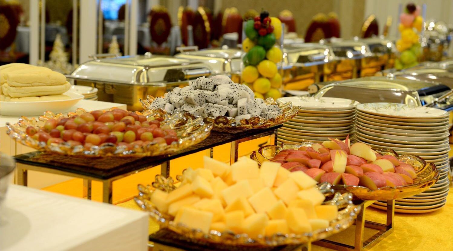 A buffet with various food items including fruits, cheeses, and meats.