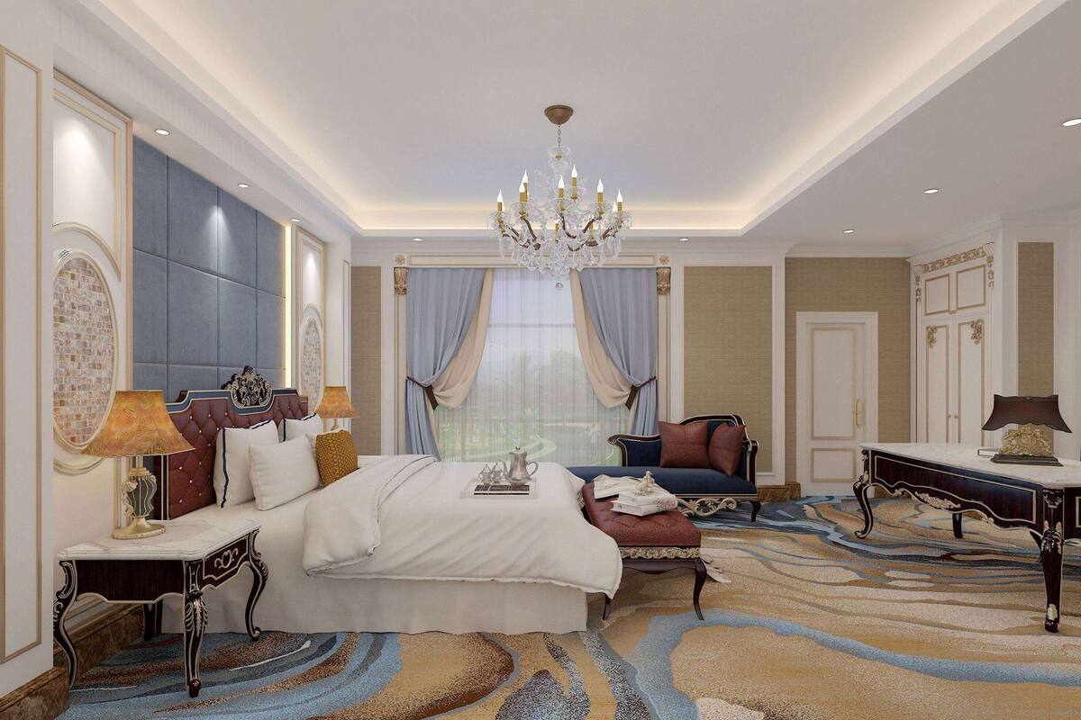 A spacious bedroom with a large bed, a sitting area with a sofa, a chandelier, and a view of the outdoors through a window.