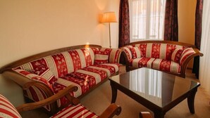 A living room with a sofa set, a coffee table, and a floor lamp. - Grand Hotel Sole (Nitra)