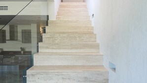 Uma escada moderna com design minimalista, que leva a um patamar com uma obra de arte emoldurada.