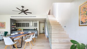 Um interior moderno com área de jantar, cozinha, escada e obras de arte.