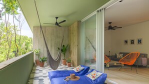 Ein Balkon mit einer Hängematte, blauen Sitzkissen und Topfpflanzen.