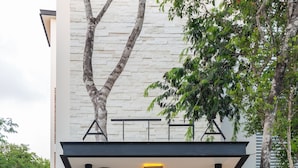 Ein moderner Hauseingang mit Holztor, überdachtem Gang und einem Baum.