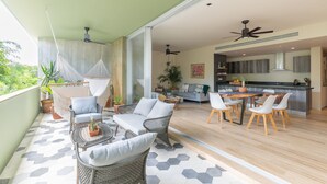 A spacious balcony with wicker furniture, a dining area with a wooden table and chairs, and a kitchen with a modern design. - Casa Julian 2BR - Attha Cenote (Tulum)