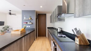 A modern kitchen with a wooden countertop, a built-in stove, and a knife block. - Casa Julian 2BR - Attha Cenote (Tulum)
