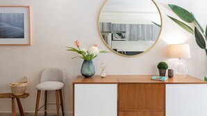 A modern room with a wooden desk, a chair, a vase with flowers, a round mirror, and a lamp. - Casa Luna 1BR by the Pool - Attha Cenote (Tulum)