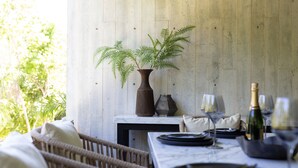 A dining table set with plates, glasses, and a bottle of champagne, with a fern plant in a vase on the wall behind. - Villa Tu-Kaán Stunning 2BR - Attha Cenote (Tulum)