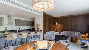 A modern kitchen with a bar area, a dining table with candles, and a living area with a sofa and chairs. - Villa Tu-Kaán Stunning 2BR - Attha Cenote (Tulum)