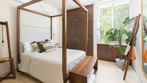 A four-poster bed with a wooden frame, a bedside table, and a bench. There is a wardrobe with a mirror and a potted plant. - Villa Tu-Kaán Stunning 2BR - Attha Cenote (Tulum)