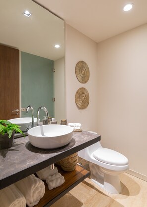 A modern bathroom with a large mirror, two sinks, a toilet, and decorative wall art.