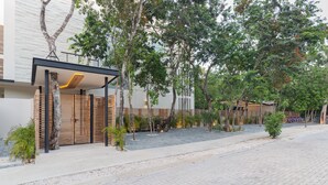 Un edificio moderno con acceso cubierto, zona de estar exterior y bicicletas estacionadas afuera.