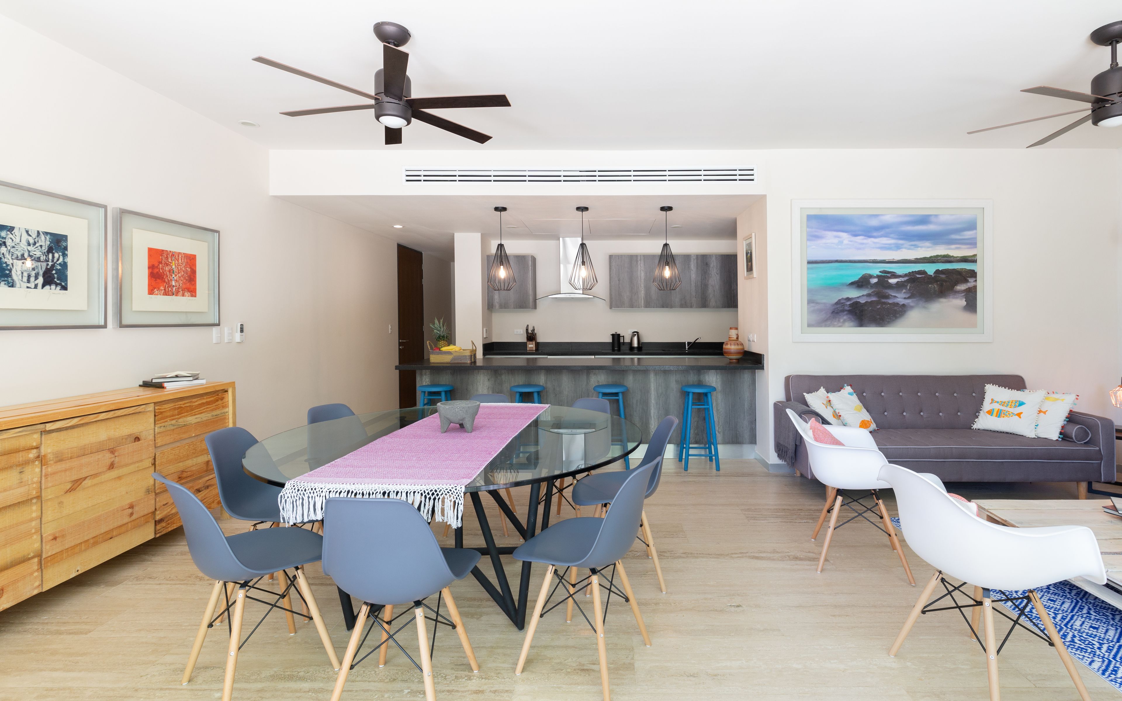 A modern kitchen with a central island, bar stools, and pendant lighting.