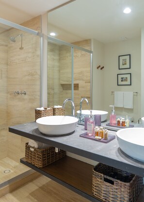 A modern bathroom with two sinks, a shower, and a large mirror. There are wicker baskets under the sinks and a towel rack on the wall. - Casa del Agua 2 BR Jungle Views - Attha Cenote (Tulum)