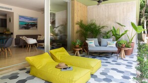 Un salón luminoso con sofás amarillos, una separadora de madera y plantas en macetas.