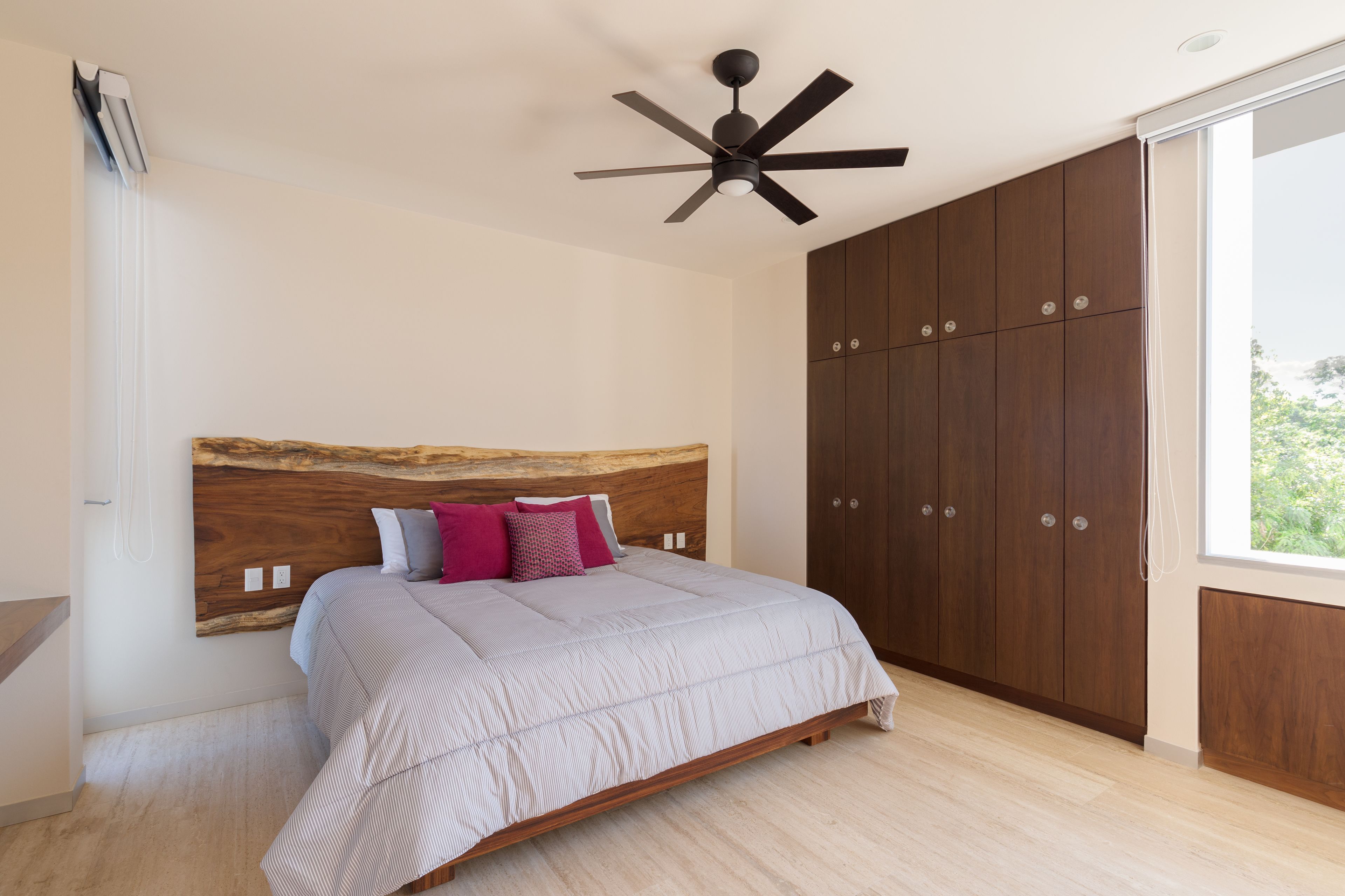 Un dormitorio con cama, cabecera de madera, armario y ventilador de techo.
