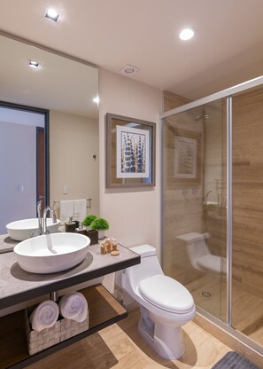 Un baño moderno con lavamanos doble, inodoro y cabina de ducha de vidrio.