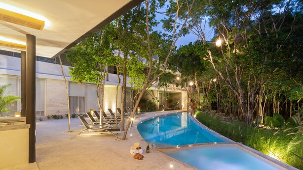 A modern outdoor swimming pool area with lounge chairs and a well-lit patio. - Villa Parota 2BR Nature Views - Attha Cenote (Tulum)