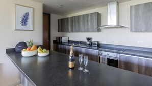 A modern kitchen with a dark countertop, a microwave, a coffee maker, and a toaster. There is a bottle of champagne and two glasses on the counter. - Villa Parota 2BR Nature Views - Attha Cenote (Tulum)