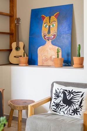 A room with a guitar, a painting, and a chair with a decorative pillow. - Casa Marisol 2BR Tulum Spirit - Attha Cenote (Tulum)
