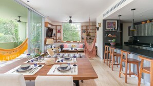 A modern kitchen with a central island, wooden bar stools, and a dining area with a table set for six. - Casa Marisol 2BR Tulum Spirit - Attha Cenote (Tulum)
